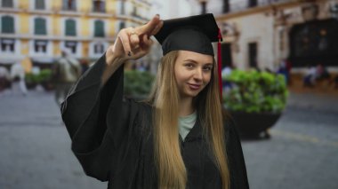 Mezuniyet üniformalı, açık hava seremonisi sırasında sokaklarda gülümseyen akademik başarı ve başarıyı temsil eden beyaz bir kadın..