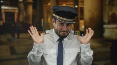 Kılavuz üniformalı sakallı genç adam tarihi bir kilise ortamında, sakin ve odaklanmış bir tavır sergiliyor..