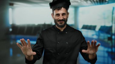 İspanyol şef sakallı. Havaalanı Terminali 1 'de beklenmedik bir seyahat ayarında neşeli ve kendine güvenen bir jest yapıyor..