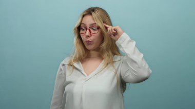 Gözlüklü genç sarışın kadın beyaz izole bir arka plan duvarından deli gibi el kol hareketi yapıyor. Kafa karışıklığı ya da delilik anlamına geliyor.