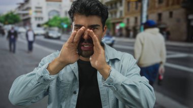 Genç ispanyol adam elleri ağzına doluyor kalabalık şehir caddesinde yoldan geçenlere bağırıyor; kamuoyu duyurusu.