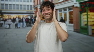 Tebessüm eden ve hareketli bir sokakta arka planda insanlar olan İspanyol bir adam şehir hayatını gözler önüne seriyor..