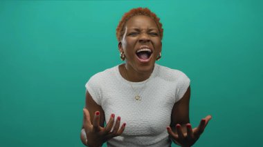 Yeşil stüdyoda çıplak elleri havada ve ağzı açık bağıran beyaz kollu bir kadın. Öfke hüsranı..