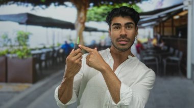 Adam açık hava restoranının terasında uzaktan kumandalı araba anahtarını işaret ediyor..