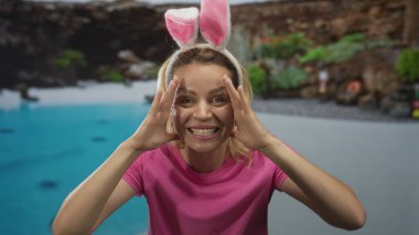 Tavşan kulaklı bir kadın havuzun önünde ellerini tutarak tatil merkezini inşa ediyor; bayram heyecanı.