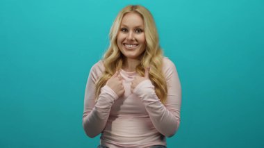 Uzun sarı saçlarıyla, parlak mavi arka planda rahat bir şekilde gülümseyen kadın neşe ve pozitifliği ifade ediyor..