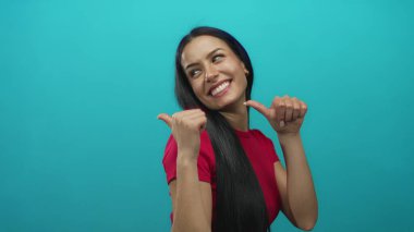 Kırmızı tişörtlü İspanyol kadın geriye doğru neşeli bir gülümsemeyle parlak mavi duvarlı izole edilmiş arka planda..