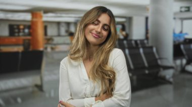 Elbise mağazasında omuzlarını saran genç sarışın bir kadın. Gözleri kapalı ve nazik bir gülümseme. Huzur verici bir rahatlık..