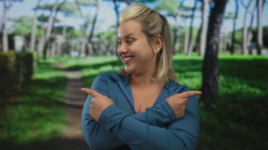 Genç sarışın kadın, açık yeşil ormanda gözleri kapalı ve işaret parmaklarıyla gülümsüyor..