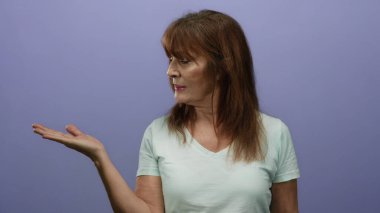 Tecrit edilmiş mor duvar arkasında el kol hareketi yapan, hafif bir gömlek giyen, olumlu bir ifade sergileyen son sınıf İspanyol kadın..