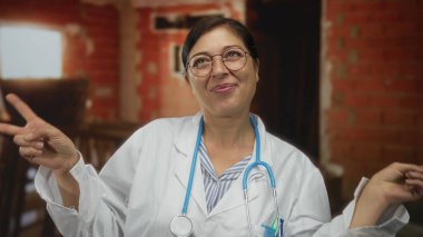 Steteskoplu kadın doktor, el yapımı barış işareti hareketi yapıyor. İyimserlik, şefkat, sağlık hizmetleri....