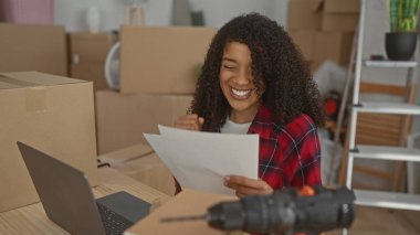 Ofis masasında dizüstü bilgisayarı, kutuları ve ofis binasında merdiveni olan bir kadın, heyecan başarısı..