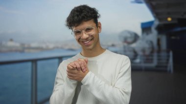 Gözlüklü, beyaz kazaklı, deniz kenarında bulanık yüzen ve arkasında yolcu gemisi olan bir adam. Mutluluk..