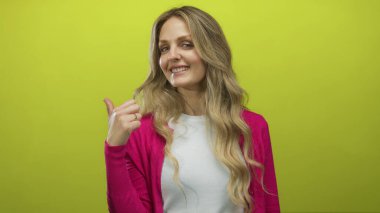 Gülümseyen kadın, sarı duvarın üzerinde genç sarışın deneği gösteren bir arka plana işaret ederken baş parmağını ileri uzatıyor..