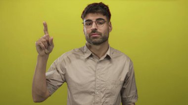 Sarı stüdyoda sağ eli ile parmaklarını sayan gözlüklü İspanyol bir adam..