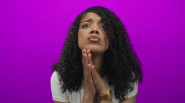 Mor arka plan altında bir stüdyoda el ele dua eden Afrikalı Amerikalı kadın. İnanç umudu sadakati..