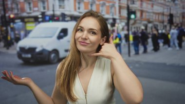 Kadın, diğer eliyle çağrı jesti yaparken el hareketleriyle sokakta açık el kol hareketi yapar; şaşkınlık merak belirsizliği şüphesi.
