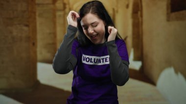 Üniversite kampüsünde gönüllü tişörtle dans eden kadın coşku ve pozitif enerji gösteriyor..