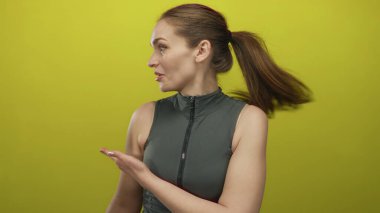 Kadın, sarı stüdyo duvarına sırtüstü uzanmış saçlarıyla yüzünü ve omzunu göstererek başını yana çeviriyor..