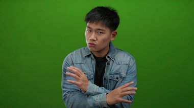 Kot ceketli genç adam, yeşil arka plana karşı olumsuz duygular besliyordu. Elleri çapraz olsun ya da olmasın, bir anlaşmazlık vardı..
