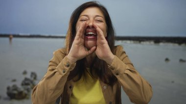 Orta yaşlı İspanyol kadın güneşli bir günde bağırmak için elleri ağız çevresine dolanıyor..