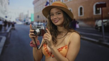 Elinde kamera olan İspanyol bir kadın, sokak manzaralarını inceliyor, genç bir turist olarak yaptığı seyahatler sırasında kentsel anları yakalıyor..