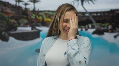 Genç sarışın kadın yüzünü havuz kenarına kapatıyor; utangaçlık, oyunculuk..