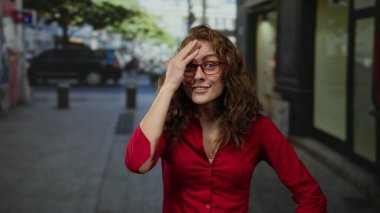 Gözlüklü ve kırmızı tişörtlü bir kadın şehir sokaklarında gündüz vakti sürpriz yapıyor..