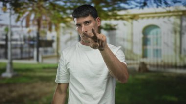 Açık havada yeşil parkta boğaza parmak attığı ve izlediği için göz göze gelen İspanyol genç adam tehdidi.