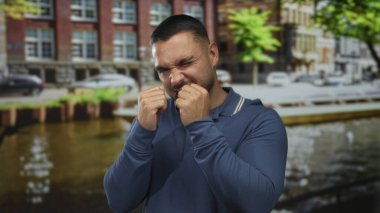 Latin kökenli genç adam gün ışığı altında kanalın kenarında yumruklarını sıkıca tutuyor. Güven azmi..