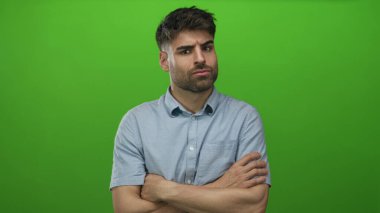 Stüdyoda kollarını kavuşturmuş İspanyol bir adam kameraya bakarken şüpheli ve içine kapanık görünüyor..