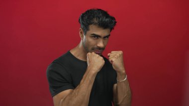 Görünür terli siyah gömlek giyen İspanyol adam stüdyoda kameraya doğru yumruklarını sıkıyor; kararlılık.