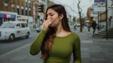 Kadın dışarıda kendini kötü hissediyor. Başı ağrıyor. Şehrin kalabalık bir caddesinde günlük yeşil giysiler içinde, şehir yaşam tarzını ve çeşitli şehirleri gösteriyor..