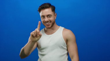 Sakallı genç adam kendini gösteriyor ve kendine güvenen bir ifadeyle mavi duvara işaret ediyor..