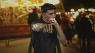 Adam, gece vakti karnaval binicilerinin önünde iki eliyle yumruk atıyor. Kararlılık..