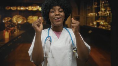 Müze sergi salonunda, steteskoplu genç Afrikalı Amerikalı kadın doktor yumruklarını sıktı; zafer.