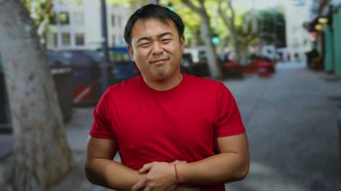 Şehirdeki sokak ortamında midesini tutan kırmızı gömlekli bir adam bulanık bir şehir geçmişine karşı rahatsızlığını dile getiriyor..