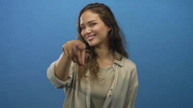 Mavi arka planda yalnız gülümseyen bir kadın elleriyle ve kalp simgesi ile öne doğru işaret ediyor ve pozitifliğini ifade ediyor..