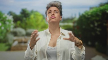 Beyaz yakalı kadın, gün ortasında ormanda çıplak omuz ve göğsü ortaya çıkarmak için beyaz gömlek yakasını kenara çeker..