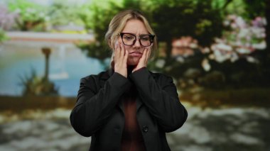 Parkta yemyeşil ve su özellikleri olan çeşitli duygular ifade eden gözlüklü bir kadın..