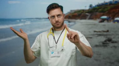Steteskoplu genç sakallı bir adam güneşli bir sahil geçmişinde parmağı olmadan sakin bir deniz kenarında tıbbi otoritesini taşır..