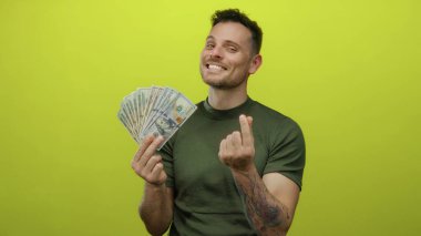 Hispanik adamın elinde dolar hayranı canlı sarı bir arka plana karşı güler. Karizma ve finansal başarı yayarken aynı zamanda neşeli bir kalp hareketi yapar..