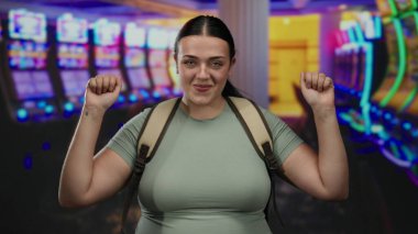 Kumarhanede kumar makinelerinin keyfini çıkaran genç bir kadın aydınlık bir ortamda heyecan ve enerji dolu bir anı yakalıyor..