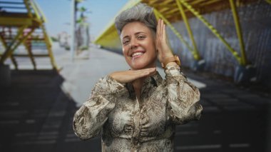 Kadın çerçeveleri, sarı iskele yanında güneşli şehir caddesinde elleri ile yüzünü çerçeveler; güven güçlendirme.