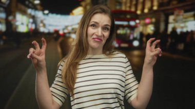 Genç beyaz kadın, geceleri hareketli caddede iki eliyle tırnak işareti yapıyor. İğneleme..