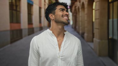 Tarihsel güneşli sokağa bakarken dişlerini gösteren adam gülümsüyor; iyimserlik merakı macera ilhamı.