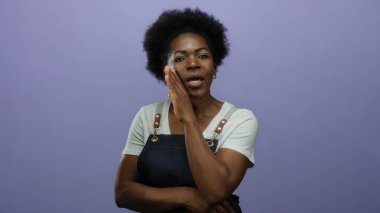 Önlük paylaşan kadın, mor arka planda gizlidir. Merakını ve gizlilik duygusunu dışa vurur. Güvenilir bir iletişimi önerir..