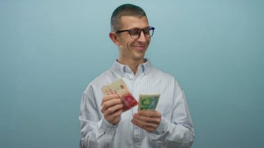 İsrail Şekel banknotlarını elinde tutan adam mavi izole bir geçmişe karşı düşünceli bir ifadeyle mali karar verme mekanizması ve para yönetimi kavramlarını iletiyor..