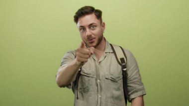 Sakallı ve sırt çantalı genç bir adam, izole edilmiş sarı bir arka planda kameraya özgüvenle ve bir gezginin ruhuyla işaret ederek beni çağırıyor..