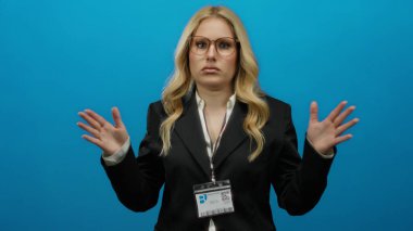 Mavi bir arkaplanda, iş elbisesi ve gözlük takan, kimlik gösteren, profesyonel bir ortamda aciliyet ve gerilimi aktaran bir kadın..